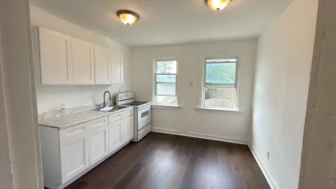 Bright kitchen with white cabinets, marble-pattern counters, a white range and wood-look flooring.
