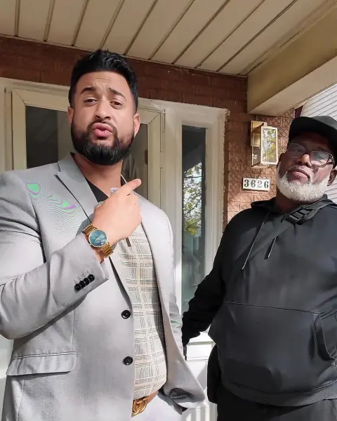 Two people talking on the porch of a brick property.